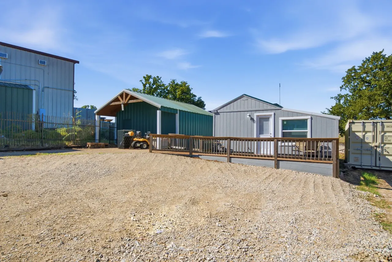 Green metal shop and the gray guest cottage with its wooden deck