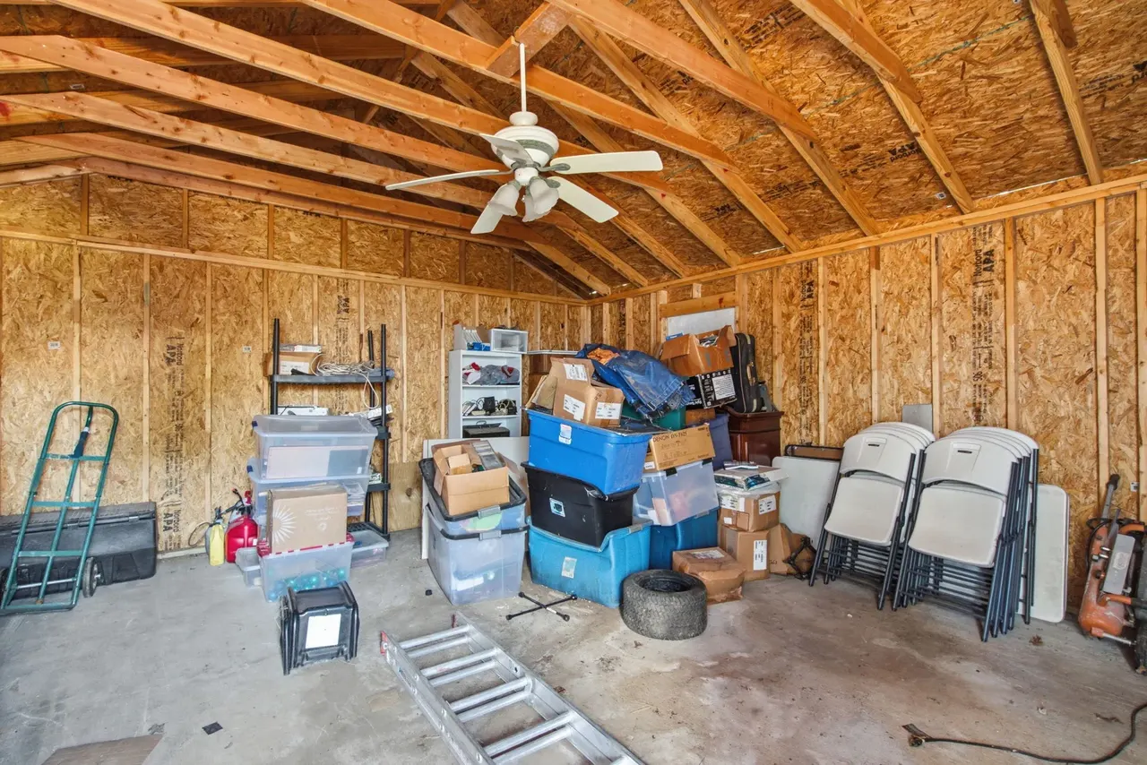 Shop interior with exposed rafters, a ceiling fan and storage bins