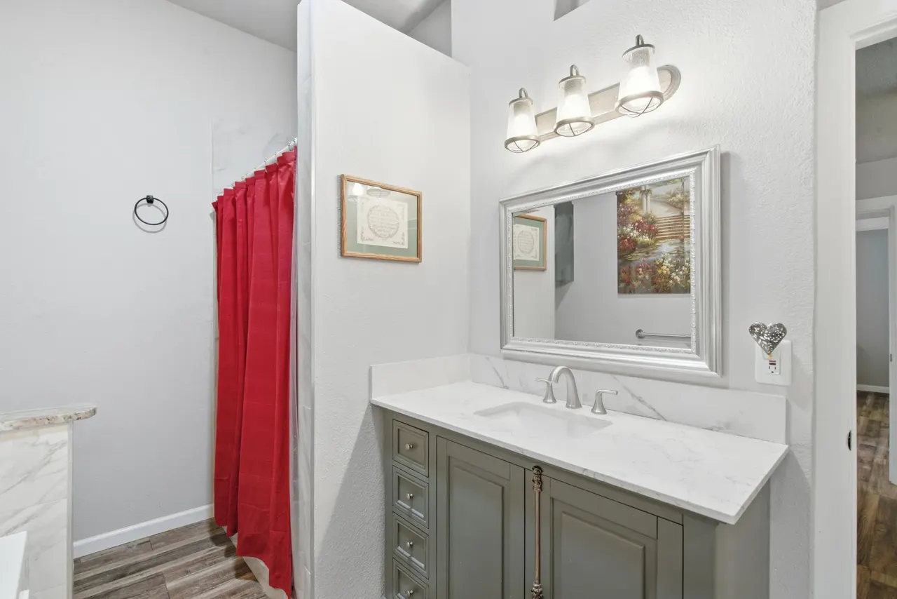 Primary bathroom with a gray vanity, white counter and framed mirror
