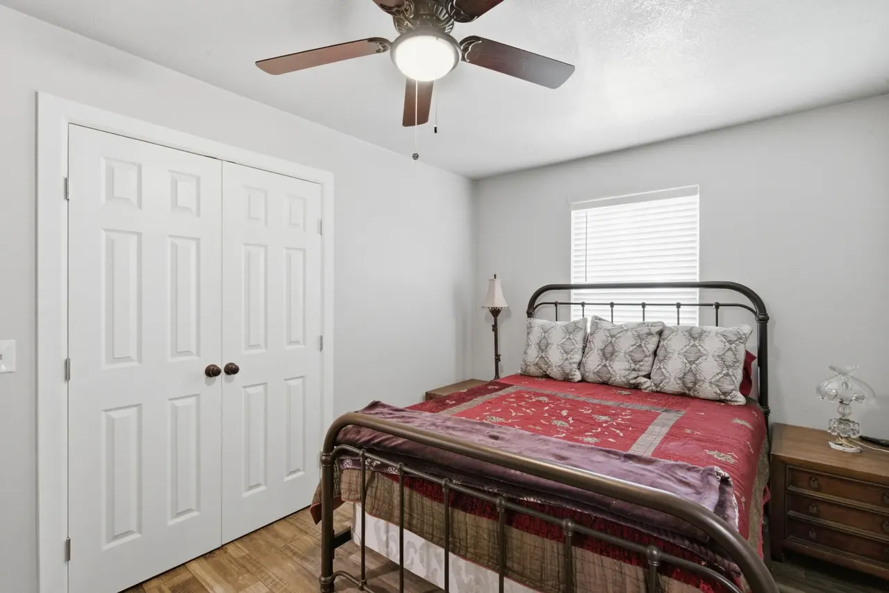 Second bedroom with a black iron bed and double closet doors