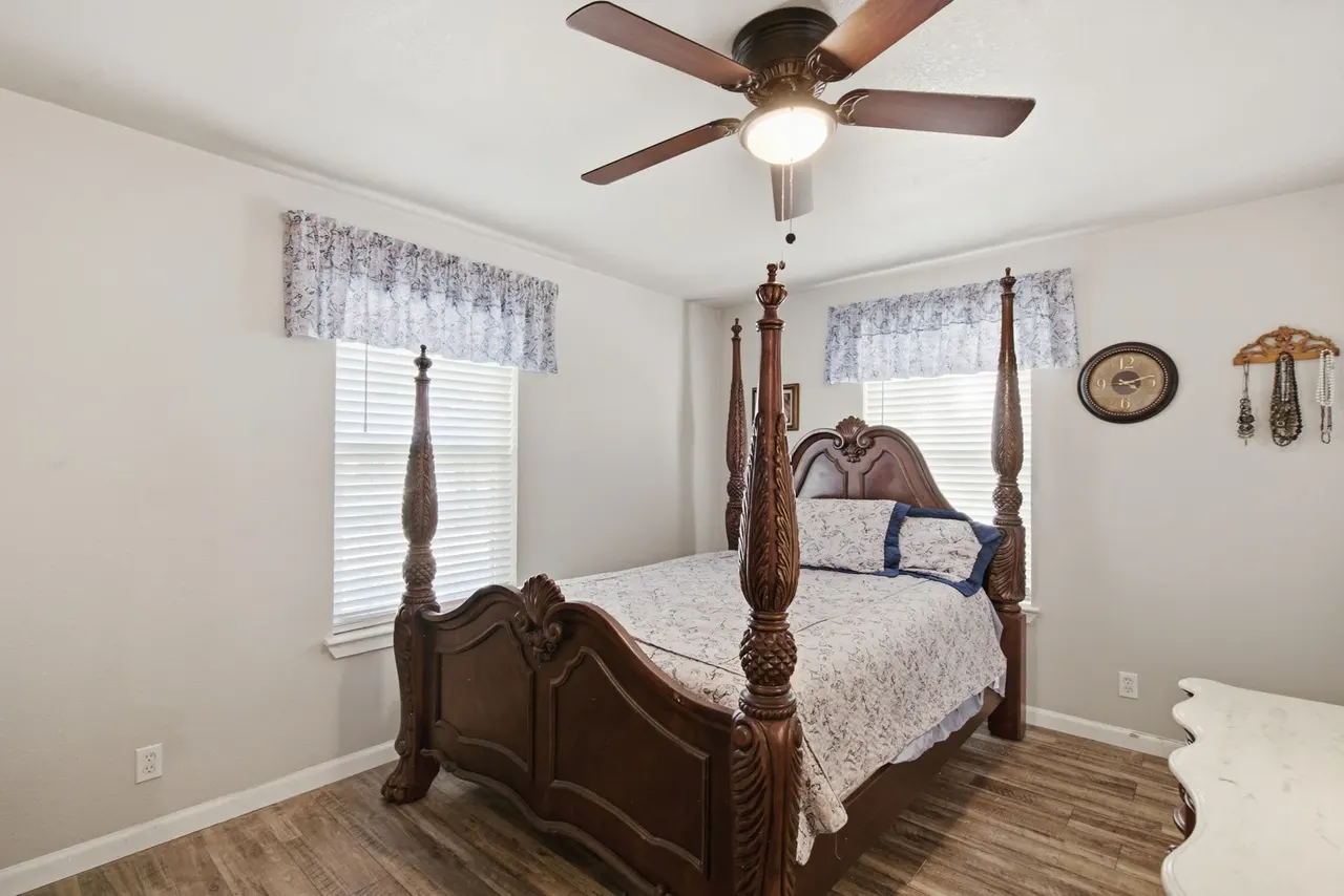 Primary bedroom with a four-poster bed between two windows