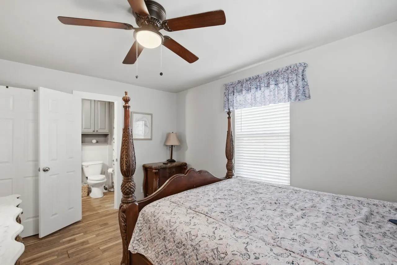 Primary bedroom with a dark wood four-poster bed and an open door to its private bathroom