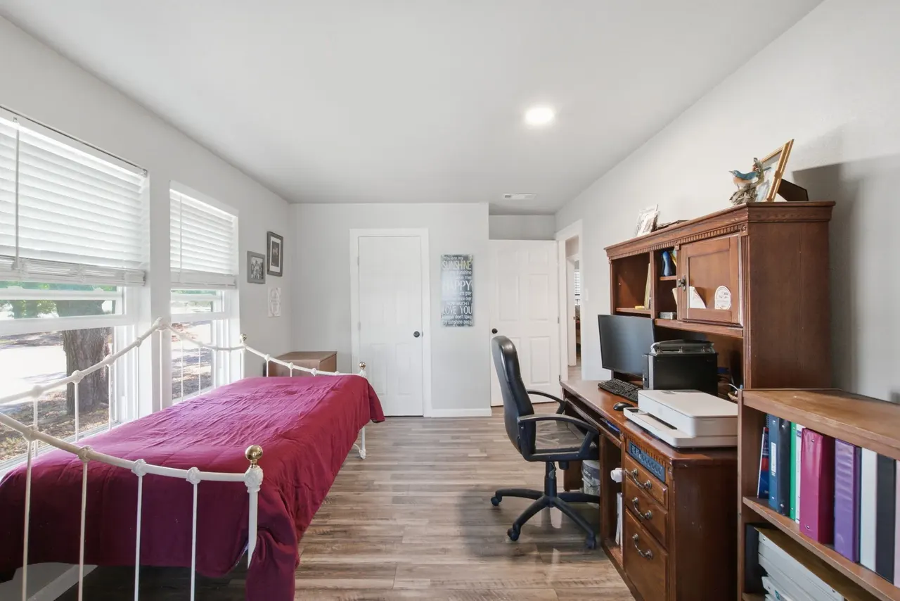 Office with a wooden desk hutch and a white daybed under the windows