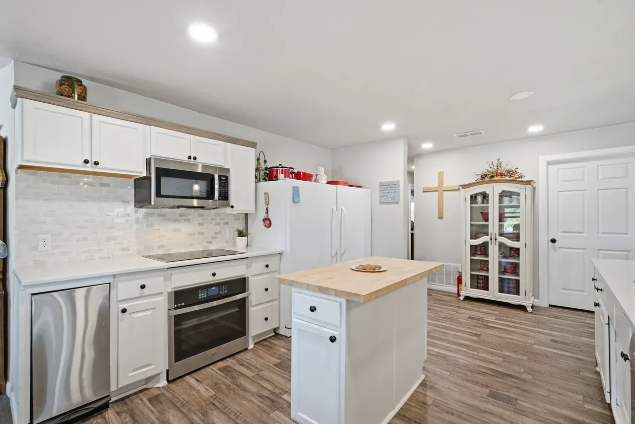 Kitchen with white cabinets, stainless appliances and a small butcher block island