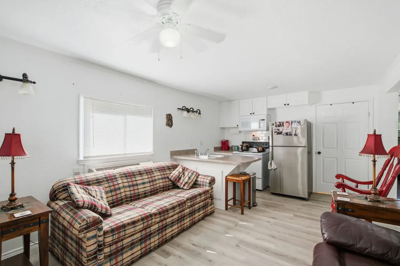 Cottage living area with a plaid sofa and the kitchenette behind