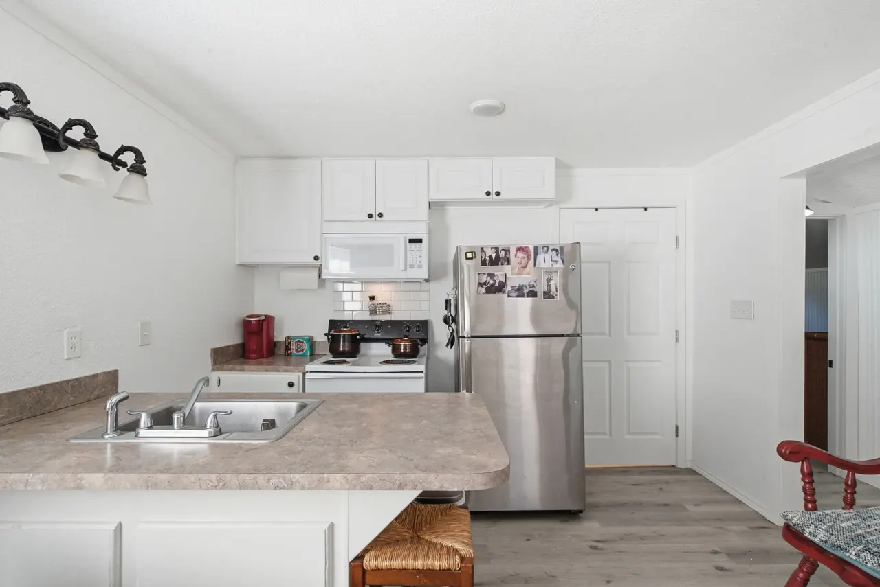 Cottage kitchen with white cabinets, a sink and a stainless fridge