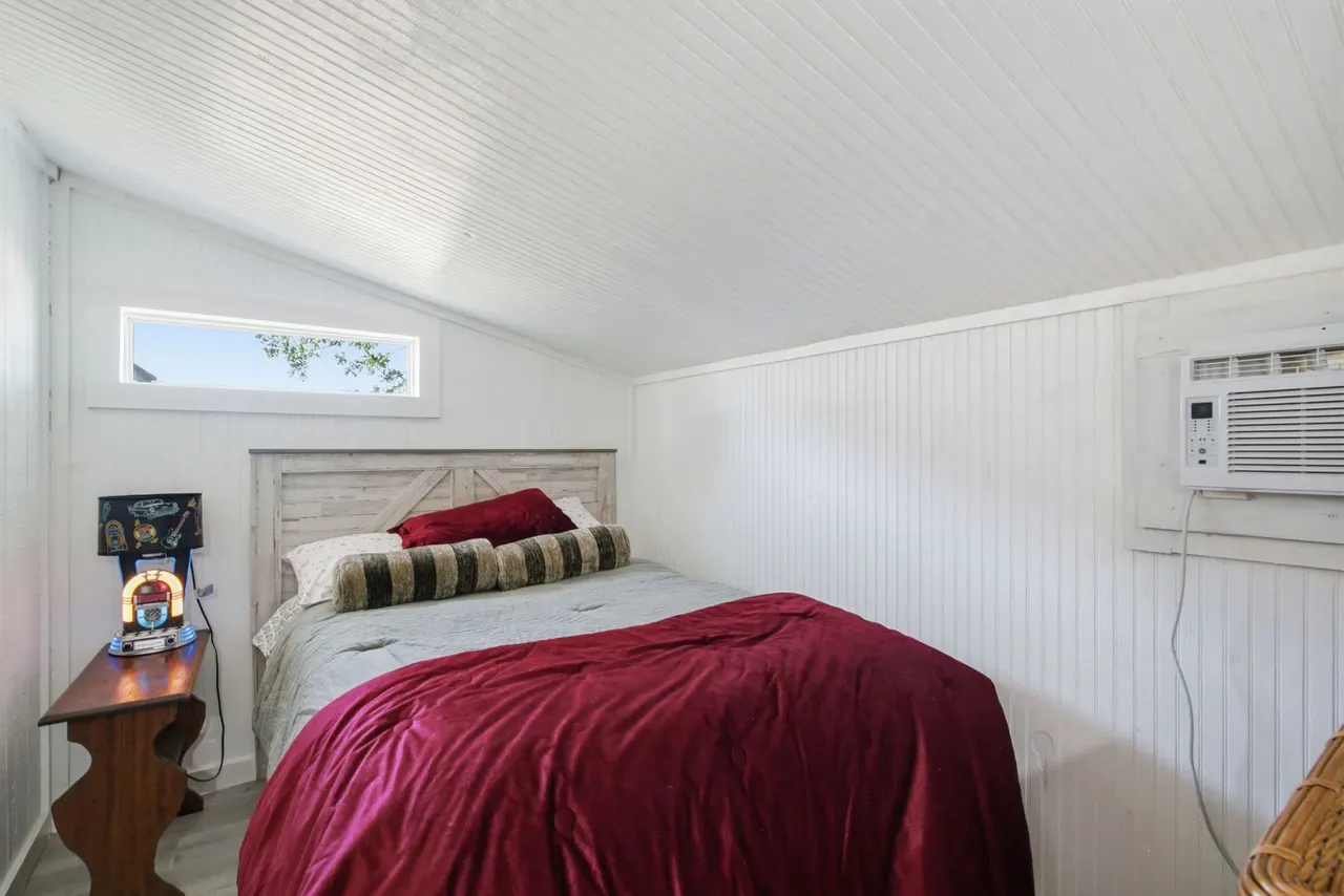 Cottage bedroom with a queen bed and a window unit air conditioner