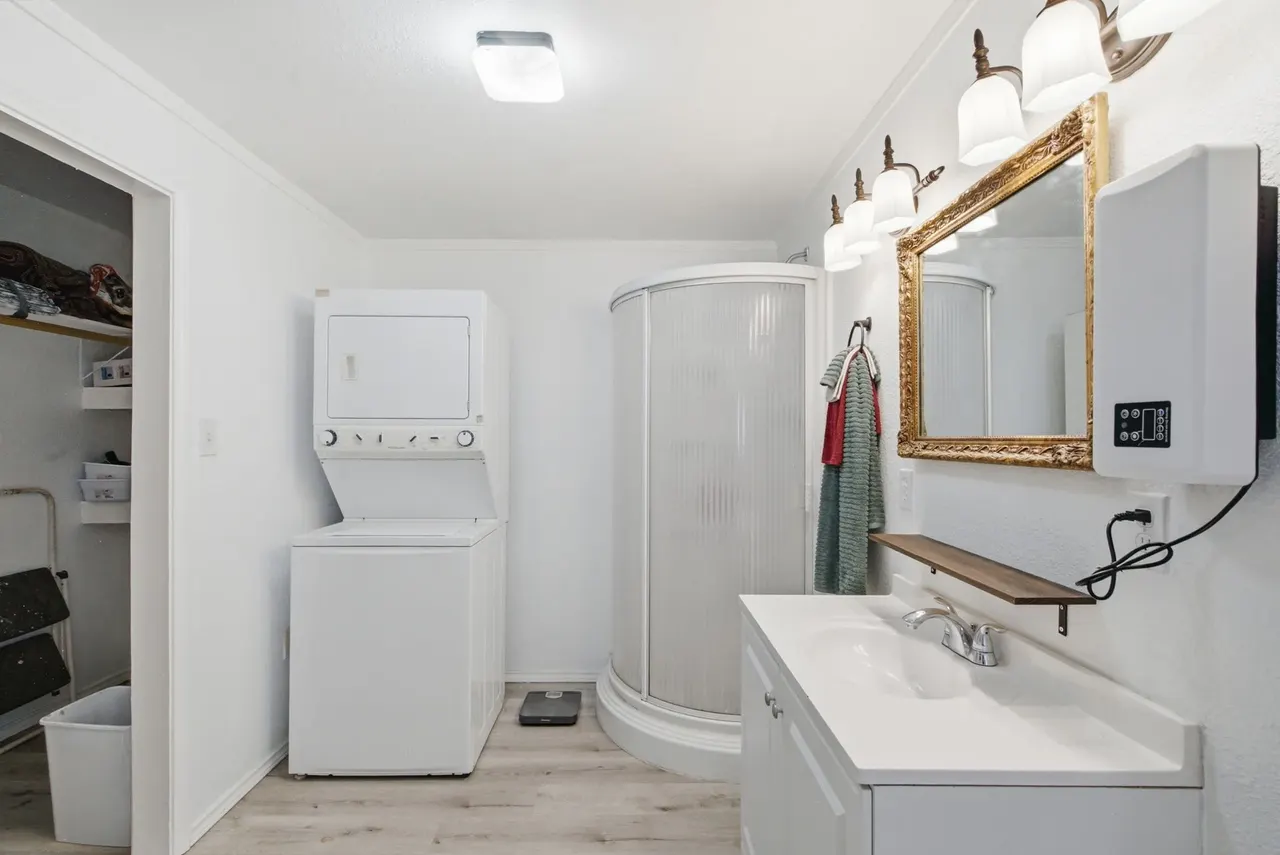 Cottage bathroom with a corner shower, vanity and stacked washer and dryer